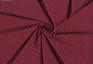 Stretch knit fabric featuring a raised honeycomb pattern with a structured, textured jacquard weave MERLOT